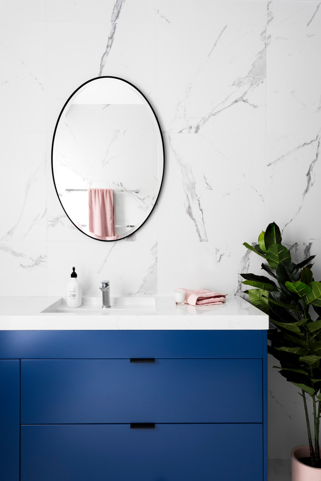 Mid-sized contemporary master bathroom in Melbourne with flat-panel cabinets, blue cabinets, an open shower, a two-piece toilet, white tile, porcelain tile, porcelain floors, an integrated sink, engineered quartz benchtops, white floor and white walls.