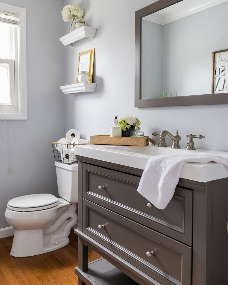 Design ideas for a country powder room in St Louis with furniture-like cabinets, brown cabinets, blue walls, light hardwood floors and engineered quartz benchtops.