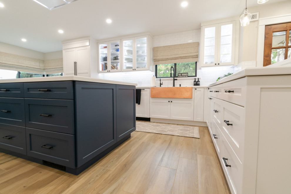 Inspiration for a huge rustic l-shaped open concept kitchen remodel in San Francisco with an undermount sink, shaker cabinets, white backsplash, ceramic backsplash, stainless steel appliances and an island