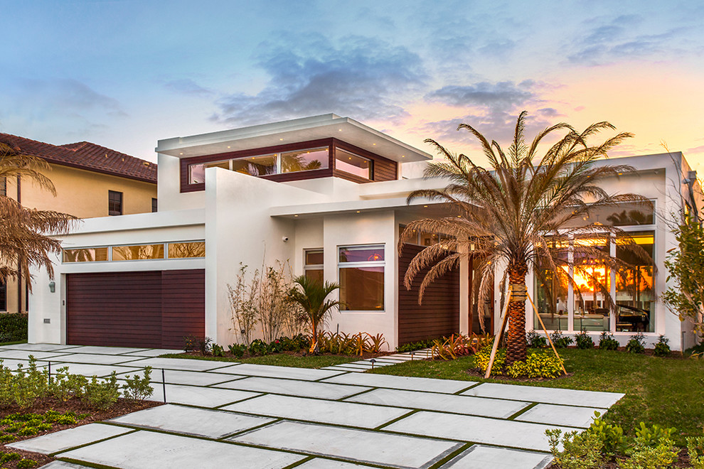 This is an example of a large contemporary two-storey stucco white house exterior in Miami with a flat roof.