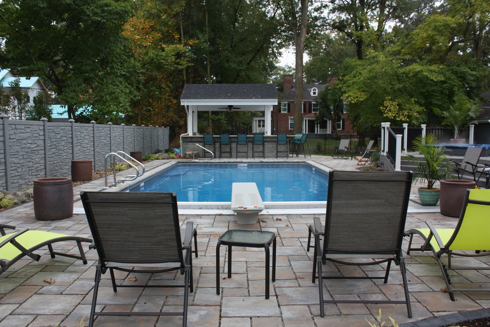 Example of a mid-sized transitional backyard rectangular and concrete paver lap hot tub design