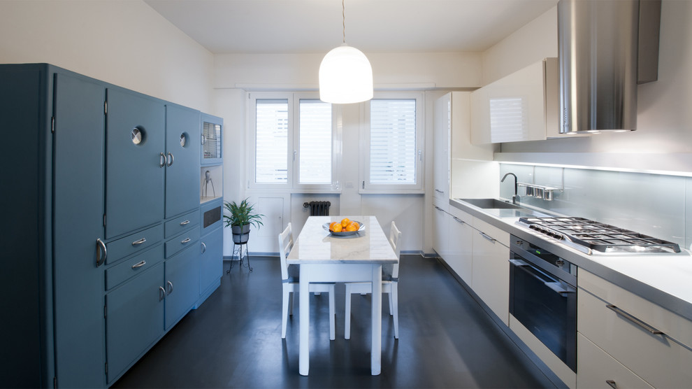 Photo of a large contemporary eat-in kitchen in Rome with an integrated sink, flat-panel cabinets, white cabinets, stainless steel benchtops, white splashback, glass sheet splashback, stainless steel appliances and porcelain floors.