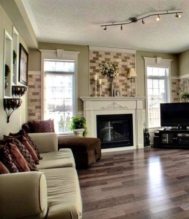 Photo of a mid-sized traditional open concept family room in Toronto with green walls, medium hardwood floors, a standard fireplace, a wood fireplace surround and a freestanding tv.