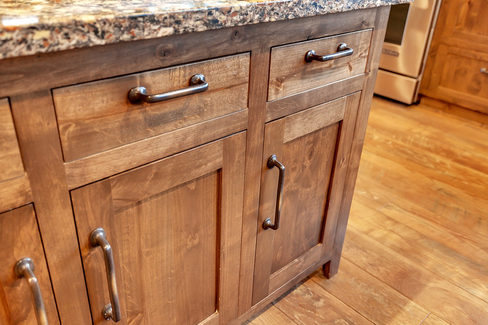 This is an example of a large transitional l-shaped eat-in kitchen in Portland with an undermount sink, shaker cabinets, medium wood cabinets, marble benchtops, grey splashback, stone slab splashback, stainless steel appliances, light hardwood floors and with island.