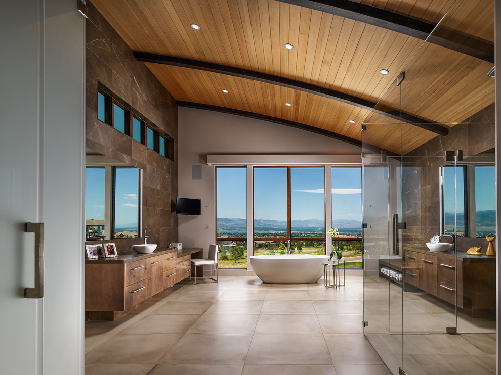 Photo of an expansive contemporary master bathroom in San Francisco with flat-panel cabinets, medium wood cabinets, a freestanding tub, a one-piece toilet, brown tile, marble, white walls, porcelain floors, a vessel sink, marble benchtops, beige floor, a hinged shower door, brown benchtops and a curbless shower.