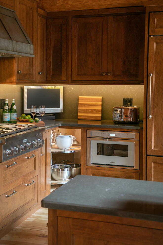 Inspiration for a mid-sized rustic l-shaped light wood floor open concept kitchen remodel in Milwaukee with recessed-panel cabinets, medium tone wood cabinets, quartz countertops, gray backsplash, stone slab backsplash, stainless steel appliances and gray countertops