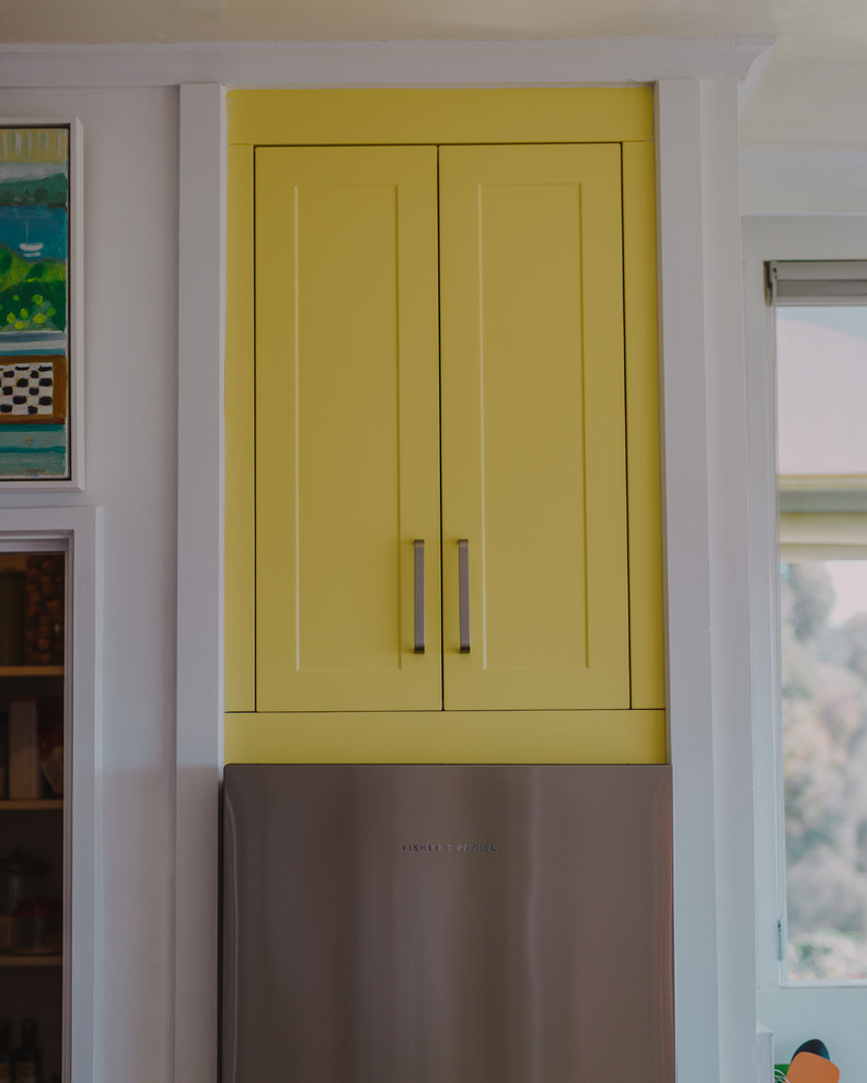 Photo of a tropical kitchen in Hobart with yellow cabinets and with island.
