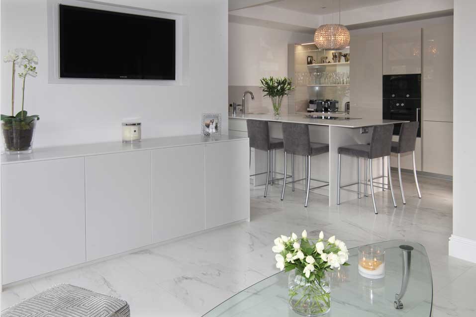 Small contemporary galley eat-in kitchen in Cheshire with a drop-in sink, beige cabinets, solid surface benchtops, mirror splashback, black appliances, porcelain floors, with island, white floor and beige benchtop.