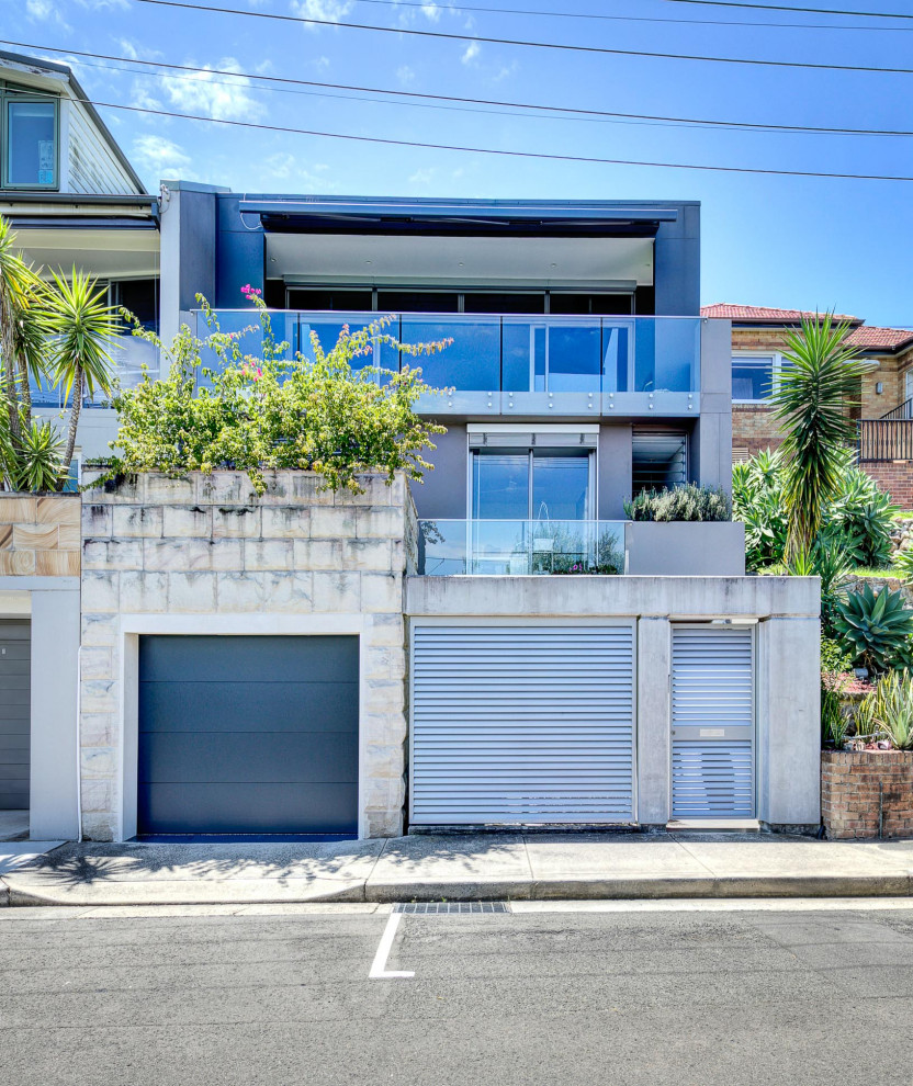 Contemporary three-storey grey house exterior in Sydney with a flat roof.