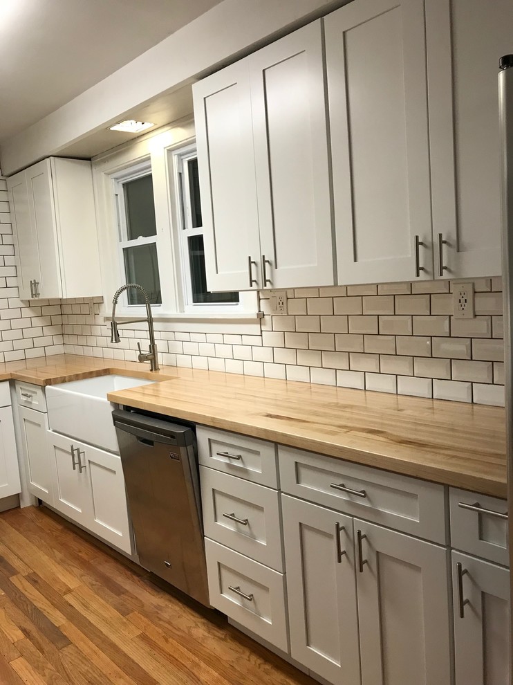 Inspiration for a mid-sized country galley eat-in kitchen in Orlando with a farmhouse sink, shaker cabinets, white cabinets, wood benchtops, white splashback, subway tile splashback, stainless steel appliances, medium hardwood floors, no island and yellow floor.