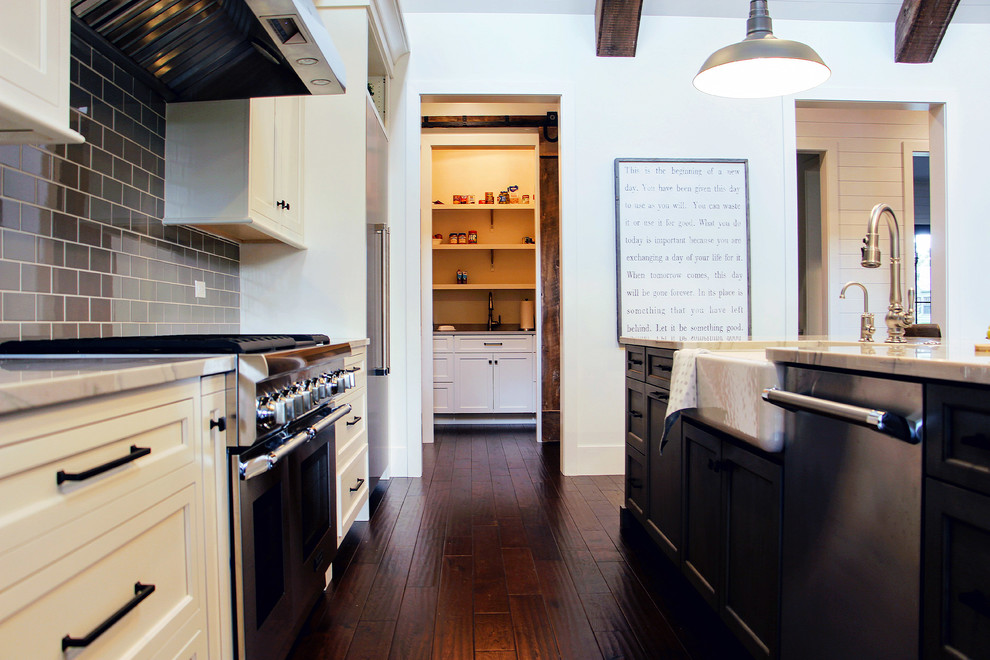 Transitional single-wall dark wood floor open concept kitchen photo in Chicago with a farmhouse sink, beaded inset cabinets, white cabinets, quartzite countertops, gray backsplash, ceramic backsplash, stainless steel appliances and an island