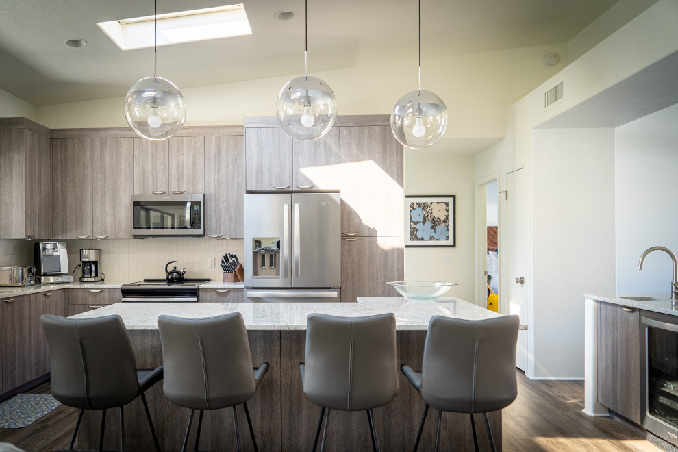 Trendy kitchen photo in Phoenix with flat-panel cabinets, gray cabinets, stainless steel appliances and an island
