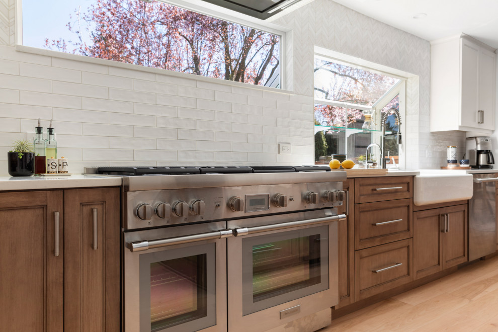 Kitchen - large transitional light wood floor and brown floor kitchen idea in Seattle with a farmhouse sink, medium tone wood cabinets, quartz countertops, white backsplash, mosaic tile backsplash, stainless steel appliances, an island and white countertops