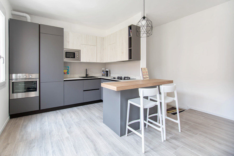 Mid-sized contemporary u-shaped separate kitchen in Other with flat-panel cabinets, grey cabinets, stainless steel appliances, a peninsula, a drop-in sink, beige splashback and white benchtop.