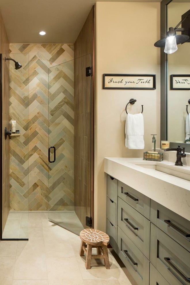 Design ideas for a mid-sized country master bathroom in Denver with shaker cabinets, an alcove shower, slate, beige walls, porcelain floors, engineered quartz benchtops, beige floor, a hinged shower door, beige benchtops, grey cabinets, multi-coloured tile, a trough sink and a built-in vanity.