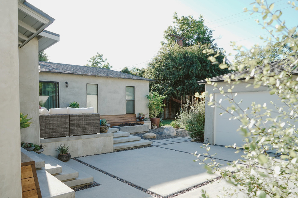 This is an example of a large modern backyard shaded xeriscape in Los Angeles with a fire feature and gravel.