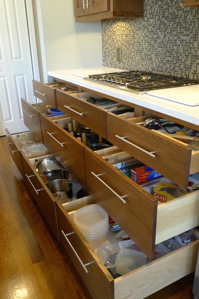 This is an example of a mid-sized transitional u-shaped eat-in kitchen in Indianapolis with an integrated sink, shaker cabinets, medium wood cabinets, solid surface benchtops, brown splashback, stainless steel appliances, medium hardwood floors and with island.