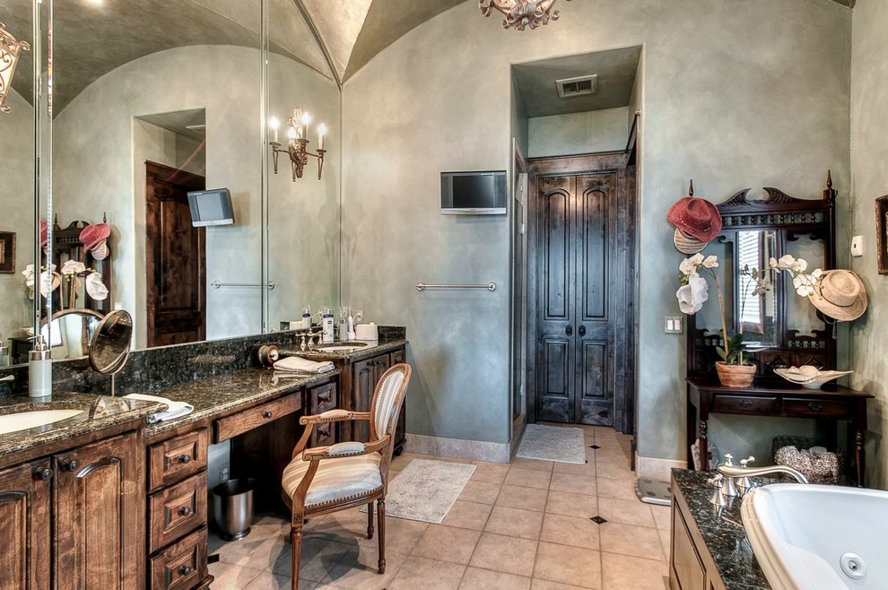 This is an example of a large mediterranean bathroom in Austin with an undermount sink, raised-panel cabinets, medium wood cabinets, granite benchtops, a drop-in tub, a two-piece toilet, beige tile, porcelain tile, green walls, porcelain floors and with a sauna.