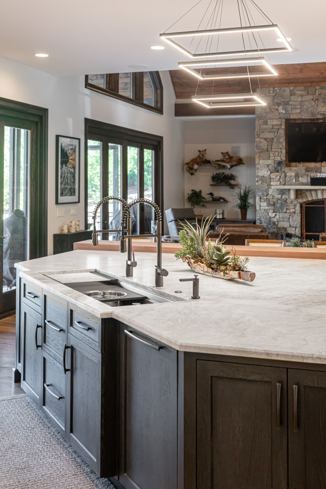 Example of a large transitional medium tone wood floor and brown floor open concept kitchen design with a double-bowl sink, flat-panel cabinets, white cabinets, quartzite countertops, beige backsplash, stainless steel appliances, an island and beige countertops