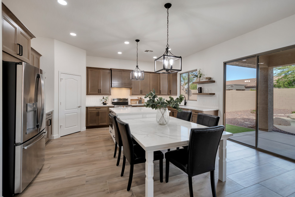 Inspiration for a mid-sized transitional u-shaped ceramic tile and brown floor eat-in kitchen remodel in Phoenix with beaded inset cabinets, brown cabinets, quartzite countertops, white backsplash, ceramic backsplash, an island and white countertops