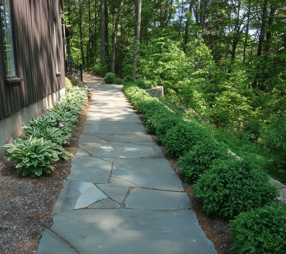 Photo of a mid-sized traditional sloped partial sun formal garden in Bridgeport with a retaining wall and natural stone pavers.
