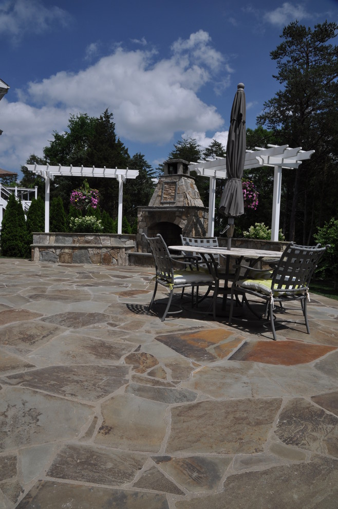 Photo of a large traditional backyard patio in DC Metro with a fire feature, natural stone pavers and a pergola.