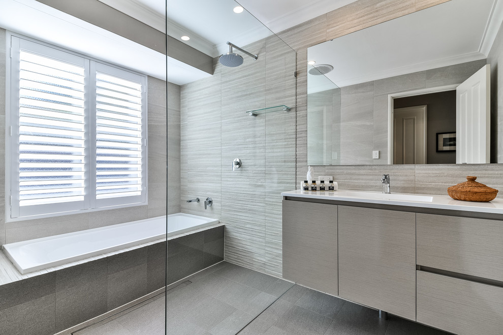 Design ideas for a mid-sized bathroom in Perth with medium wood cabinets, a drop-in tub, an open shower, a one-piece toilet, gray tile, stone tile, grey walls and an integrated sink.