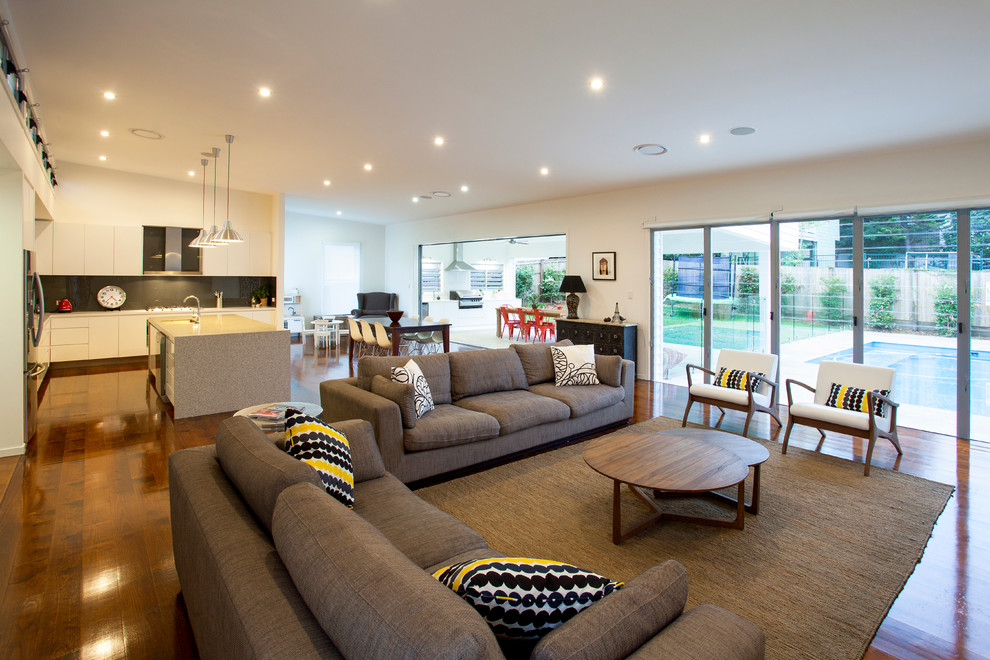 This is an example of an expansive contemporary open concept living room in Brisbane with white walls, medium hardwood floors and a wall-mounted tv.