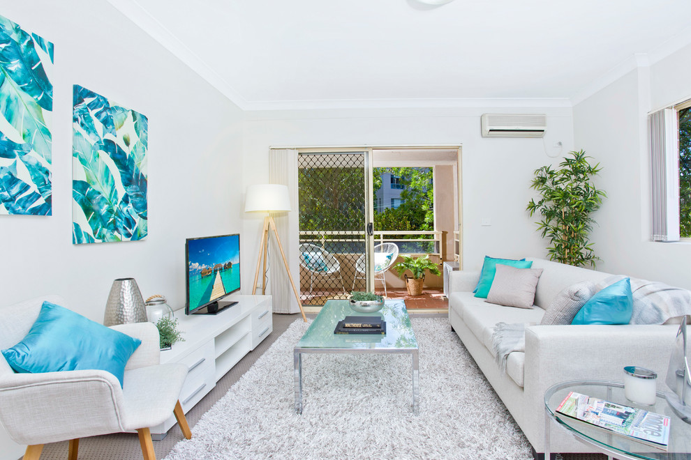 Beach style enclosed family room in Sydney with white walls, carpet, a freestanding tv and grey floor.