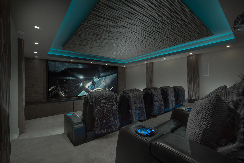 This is an example of a large modern enclosed home theatre in Salt Lake City with brown walls, carpet, a projector screen and grey floor.