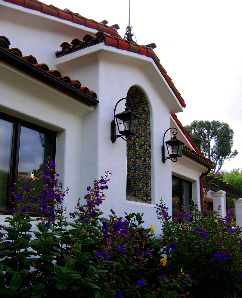Photo of a mid-sized mediterranean one-storey stucco white house exterior in Santa Barbara with a clipped gable roof and a tile roof.