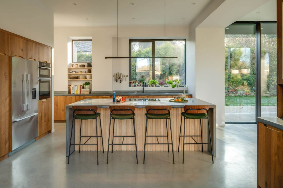 This is an example of a large contemporary l-shaped kitchen/diner in Other with flat-panel cabinets, medium wood cabinets, concrete worktops, an island and grey worktops.