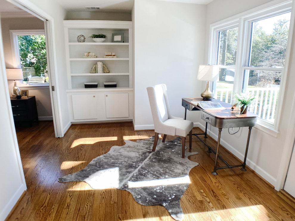 Small transitional home office in DC Metro with a library, white walls, medium hardwood floors, no fireplace, a freestanding desk and brown floor.