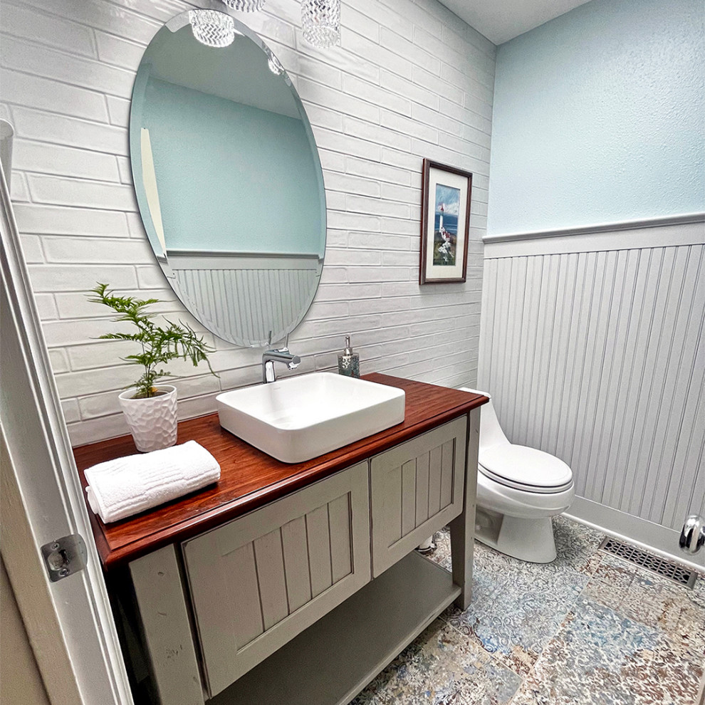 Inredning av ett modernt litet röd rött badrum, med möbel-liknande, grå skåp, en toalettstol med hel cisternkåpa, grå kakel, tunnelbanekakel, grå väggar, ett fristående handfat, träbänkskiva och flerfärgat golv