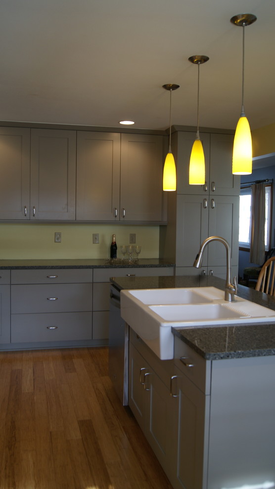 Photo of a large country l-shaped open plan kitchen in Chicago with a farmhouse sink, flat-panel cabinets, grey cabinets, quartz benchtops, stainless steel appliances, bamboo floors and with island.