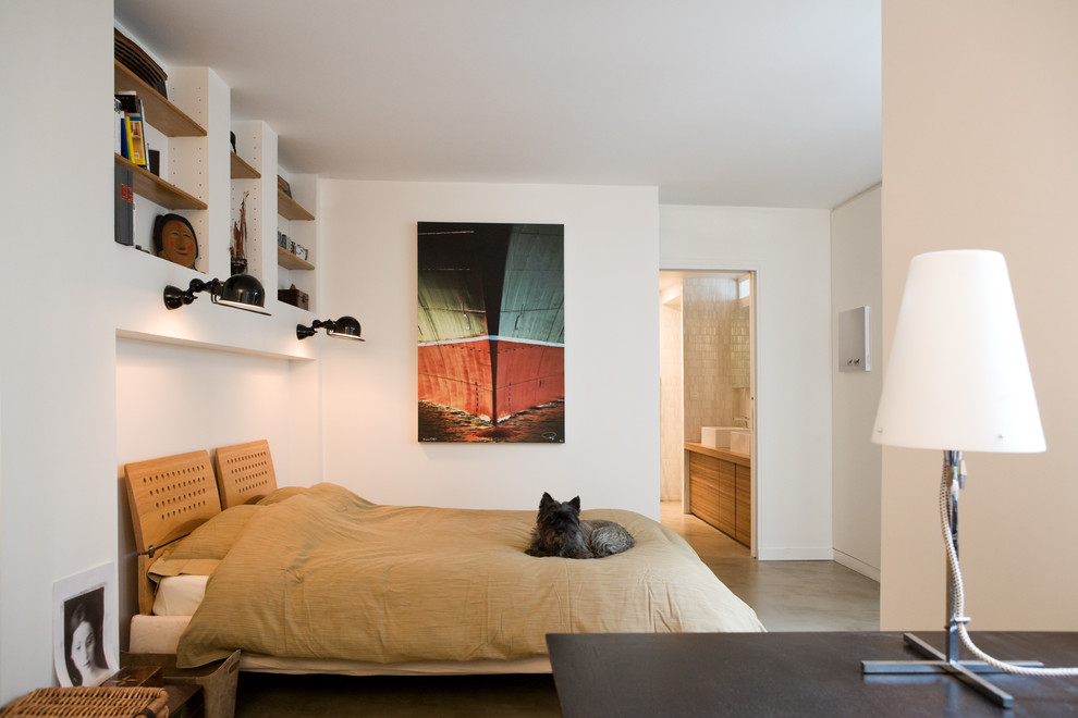 This is an example of a mid-sized contemporary master bedroom in Paris with white walls and concrete floors.