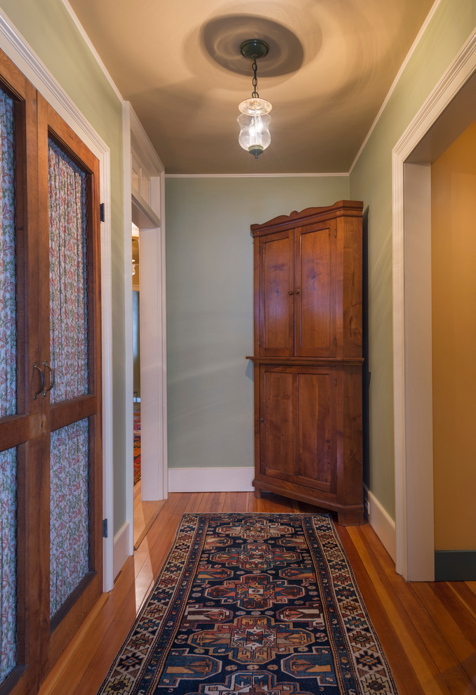 Photo of a large country hallway in Burlington with green walls and light hardwood floors.