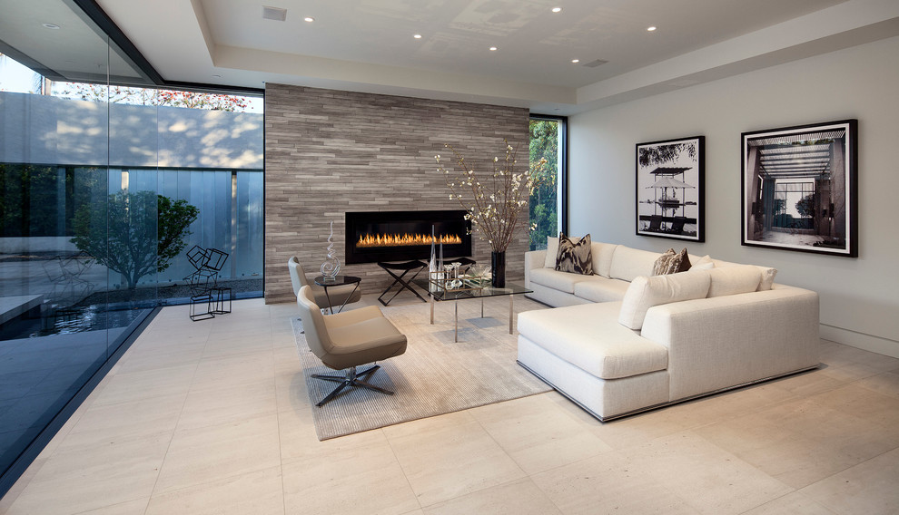 This is an example of a large contemporary formal open concept living room in Los Angeles with grey walls, travertine floors, a standard fireplace, a stone fireplace surround, no tv and beige floor.
