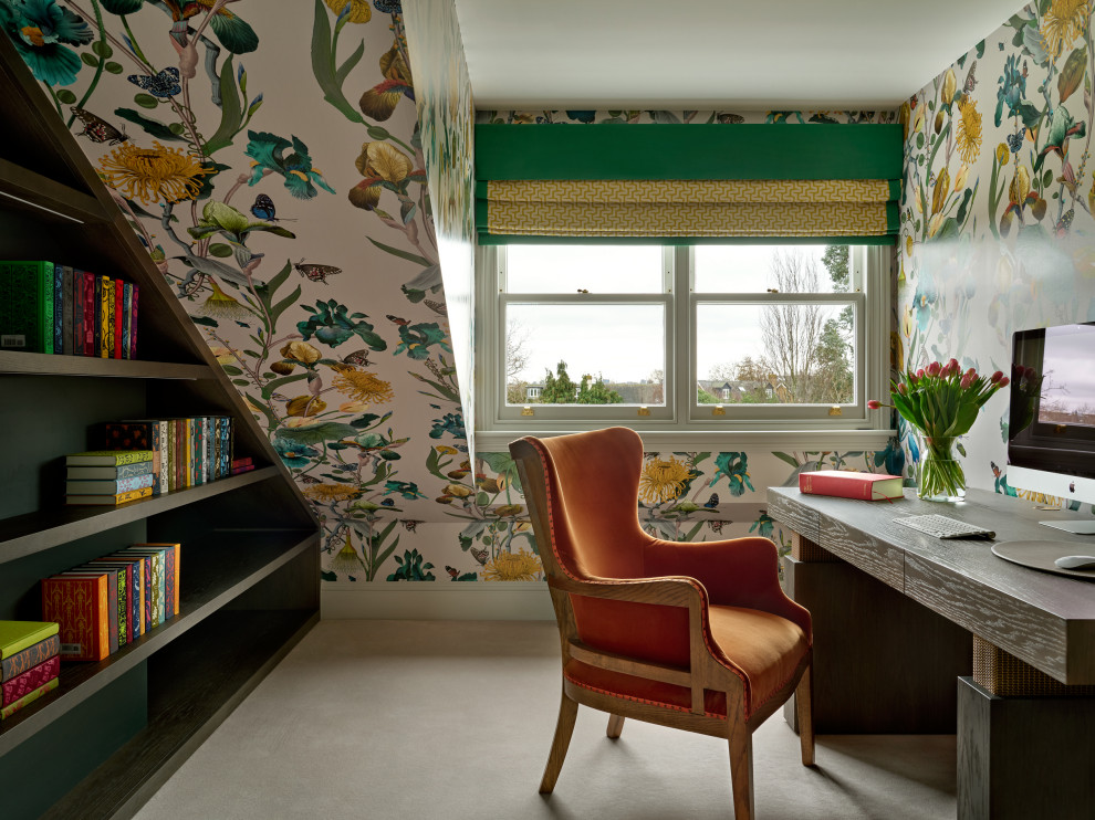 This is an example of a large transitional home office in London with a library, carpet and a freestanding desk.