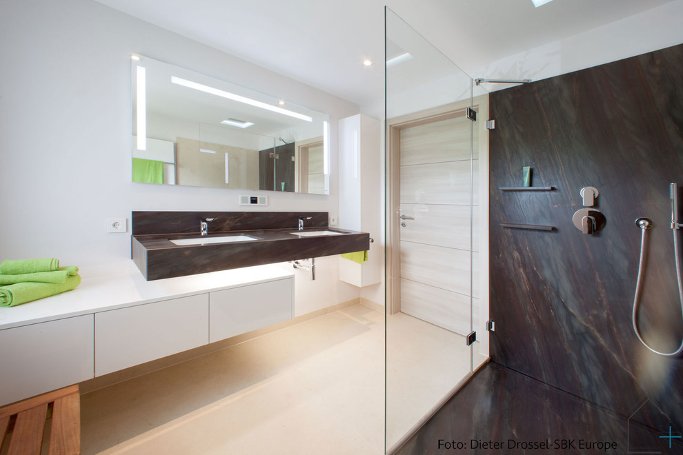 Inspiration for a small contemporary 3/4 bathroom in Stuttgart with flat-panel cabinets, white cabinets, a curbless shower, a wall-mount toilet, beige tile, stone slab, beige walls, marble floors, an undermount sink and marble benchtops.