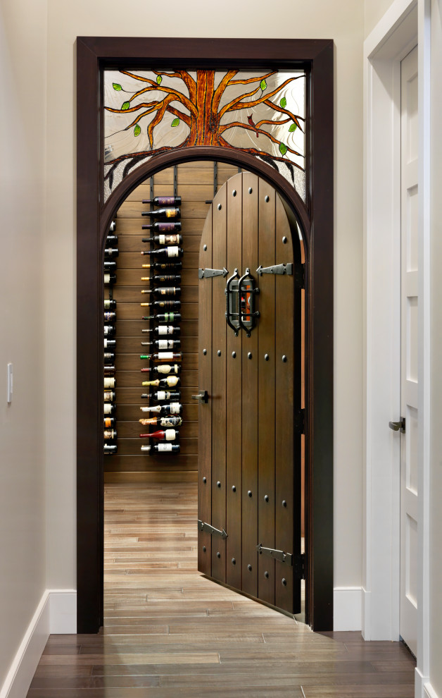 Design ideas for a mid-sized transitional wine cellar in Cincinnati with medium hardwood floors, display racks and brown floor.