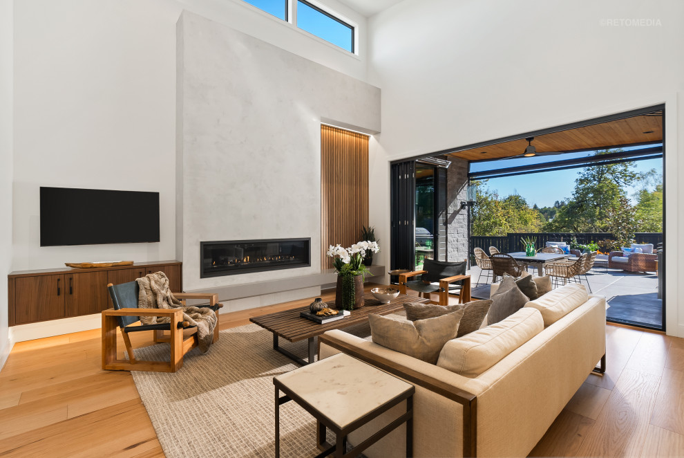 Photo of a large modern open concept living room in Portland with white walls, light hardwood floors, a ribbon fireplace, a plaster fireplace surround, a wall-mounted tv, brown floor and vaulted.