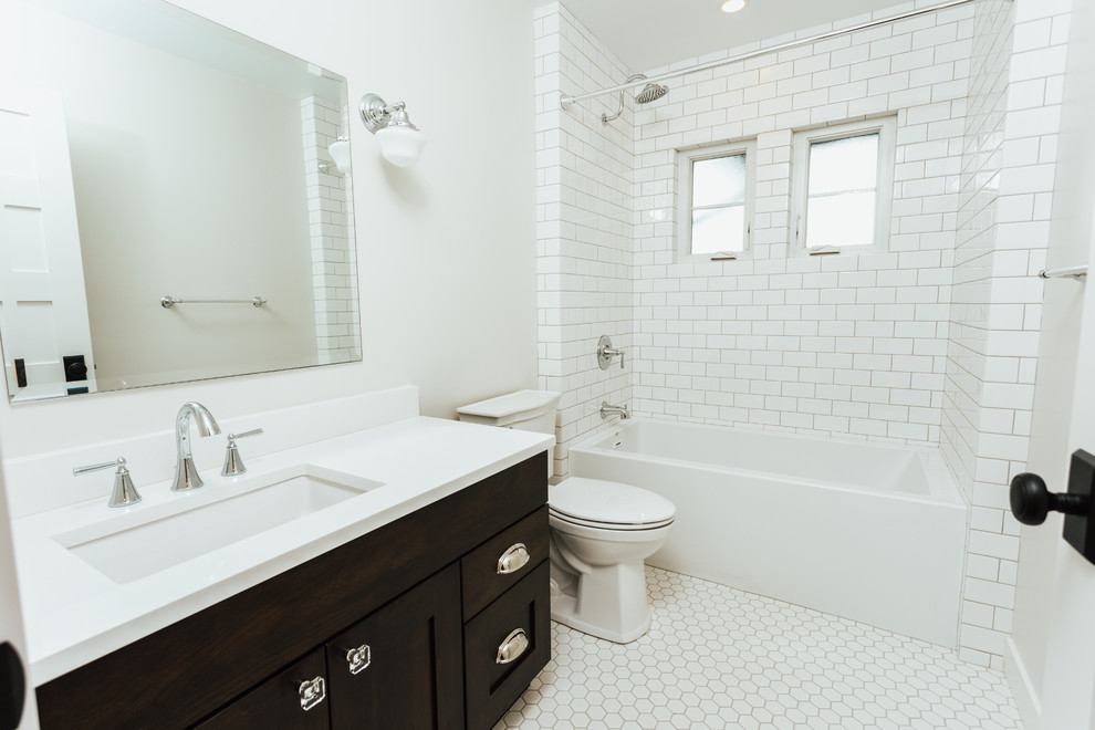 Design ideas for a mid-sized arts and crafts bathroom in Seattle with recessed-panel cabinets, dark wood cabinets, an alcove tub, a shower/bathtub combo, a two-piece toilet, white tile, subway tile, white walls, ceramic floors, an undermount sink, quartzite benchtops, white floor, a shower curtain and white benchtops.