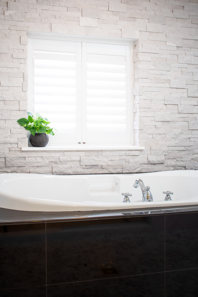 This is an example of a mid-sized asian wet room bathroom in Omaha with a japanese tub, white tile, porcelain tile, white walls, pebble tile floors, grey floor and a hinged shower door.