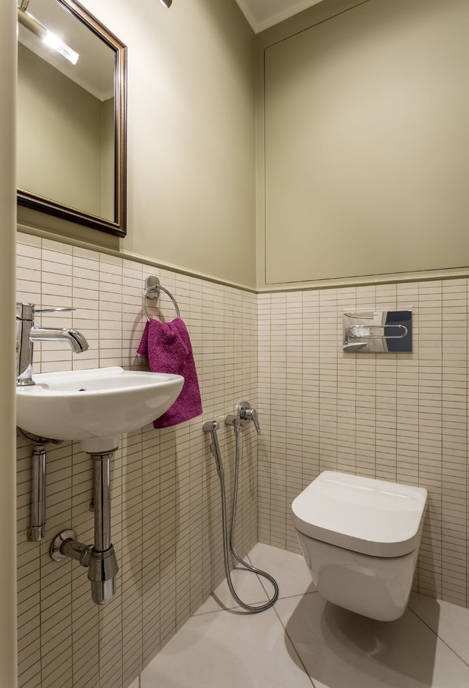 This is an example of a small contemporary powder room in Moscow with a wall-mount toilet, a wall-mount sink, beige tile, beige walls and white floor.