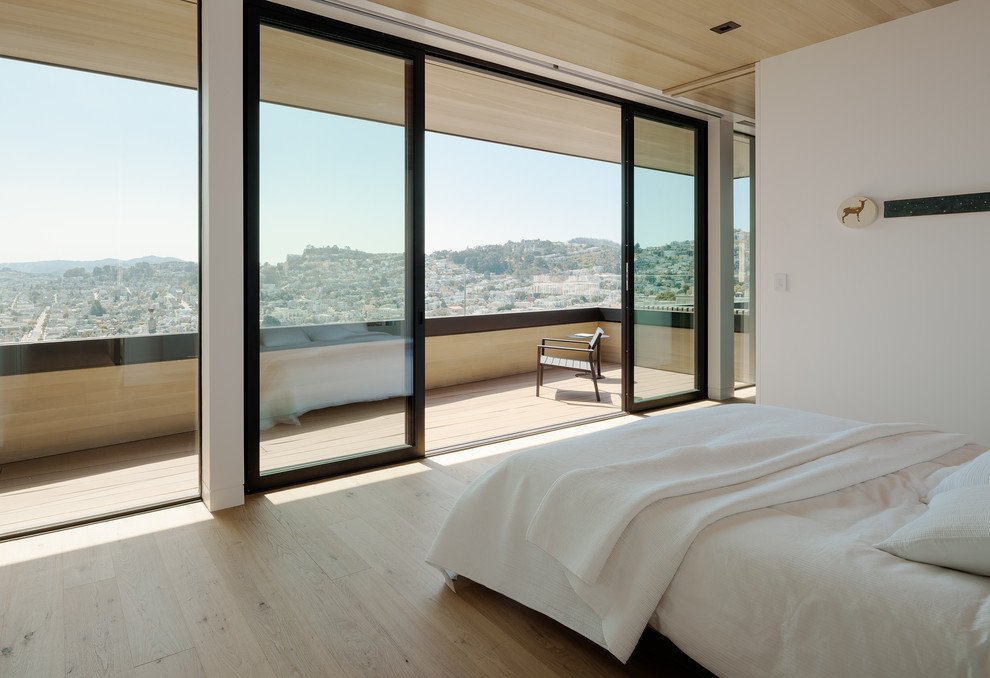 This is an example of a contemporary bedroom in San Diego with white walls, light hardwood floors and beige floor.