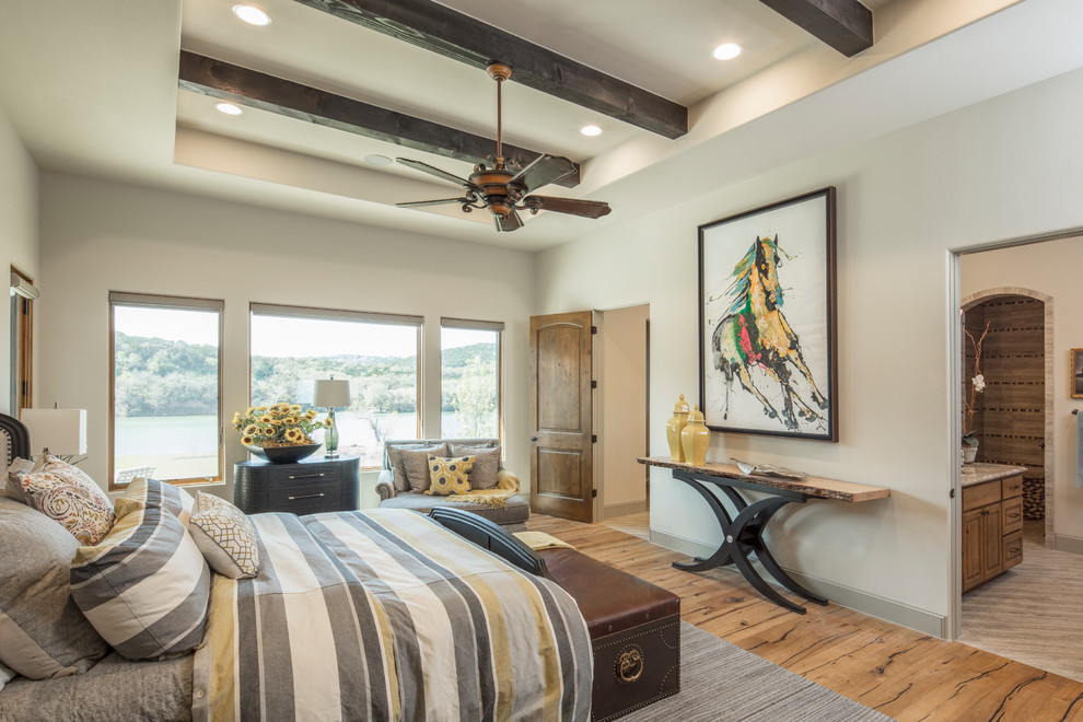 Inspiration for a large mediterranean master bedroom in Austin with white walls and light hardwood floors.