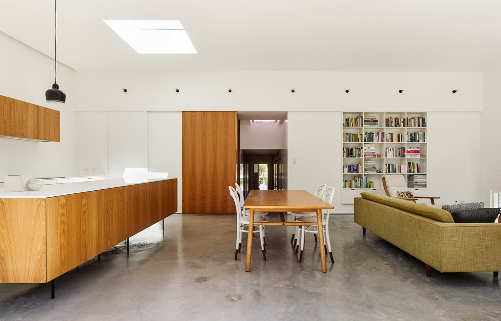 Contemporary open concept family room in Sydney with a library, white walls and concrete floors.