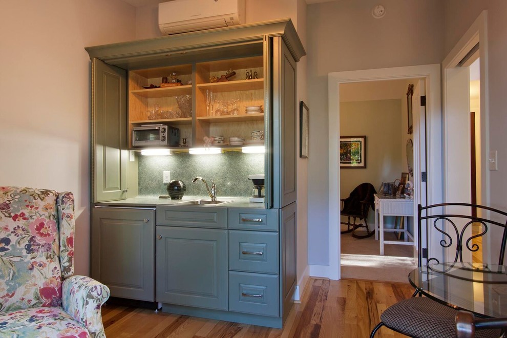 Small eclectic single-wall wet bar in Other with raised-panel cabinets and light hardwood floors.