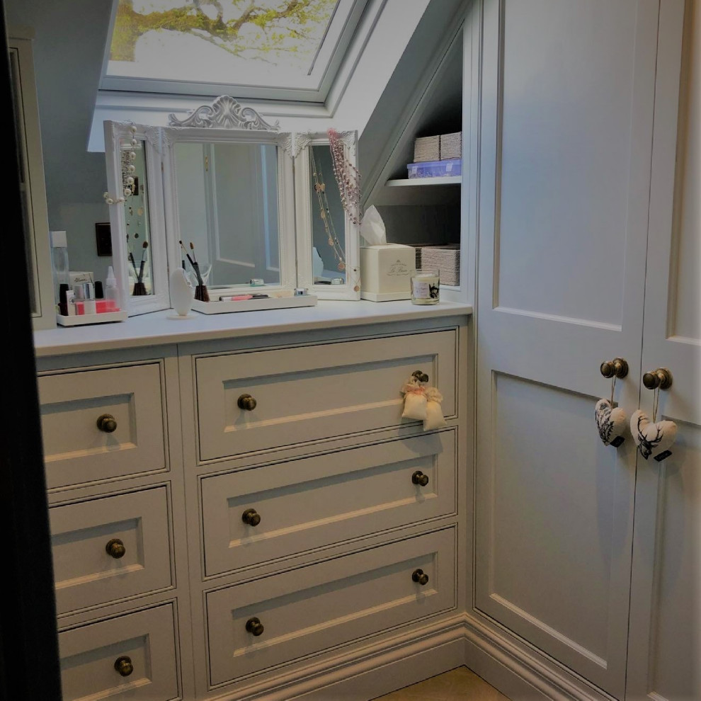 Design ideas for a small traditional walk-in wardrobe for women in Sussex with recessed-panel cabinets, blue cabinets and medium hardwood flooring.